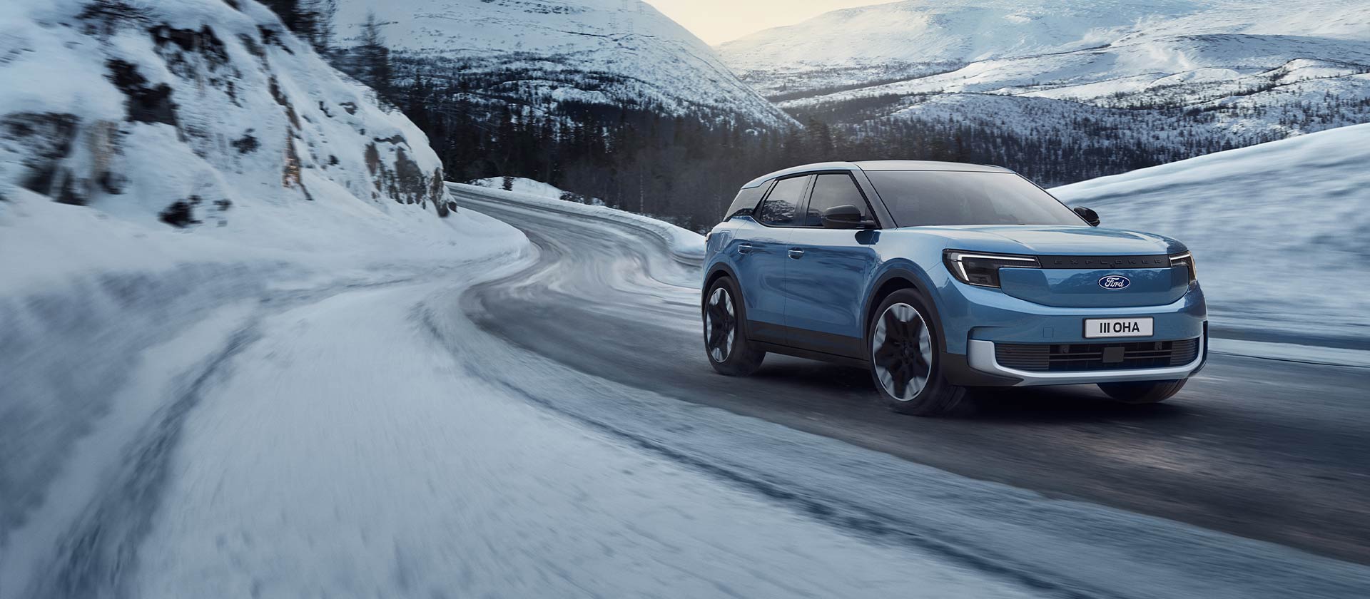 Un Ford Explorer électrique bleu sur une route de montagne enneigée pour illustrer les performances et l’autonomie en hiver.