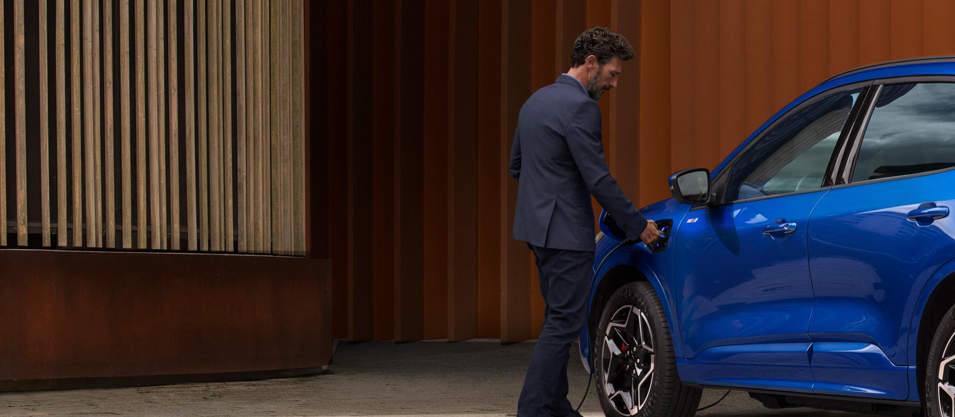 Une personne branche un véhicule hybride rechargeable Ford sur un chargeur.