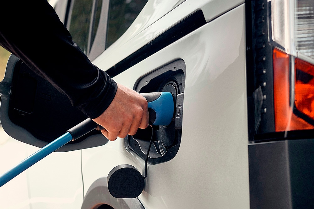 Une personne connecte un câble de recharge à un véhicule électrique Ford.