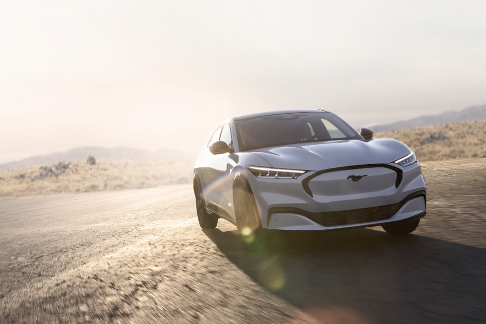 Une Ford Mustang Mach-E GT électrique de couleur argentée roule sur une route panoramique.
