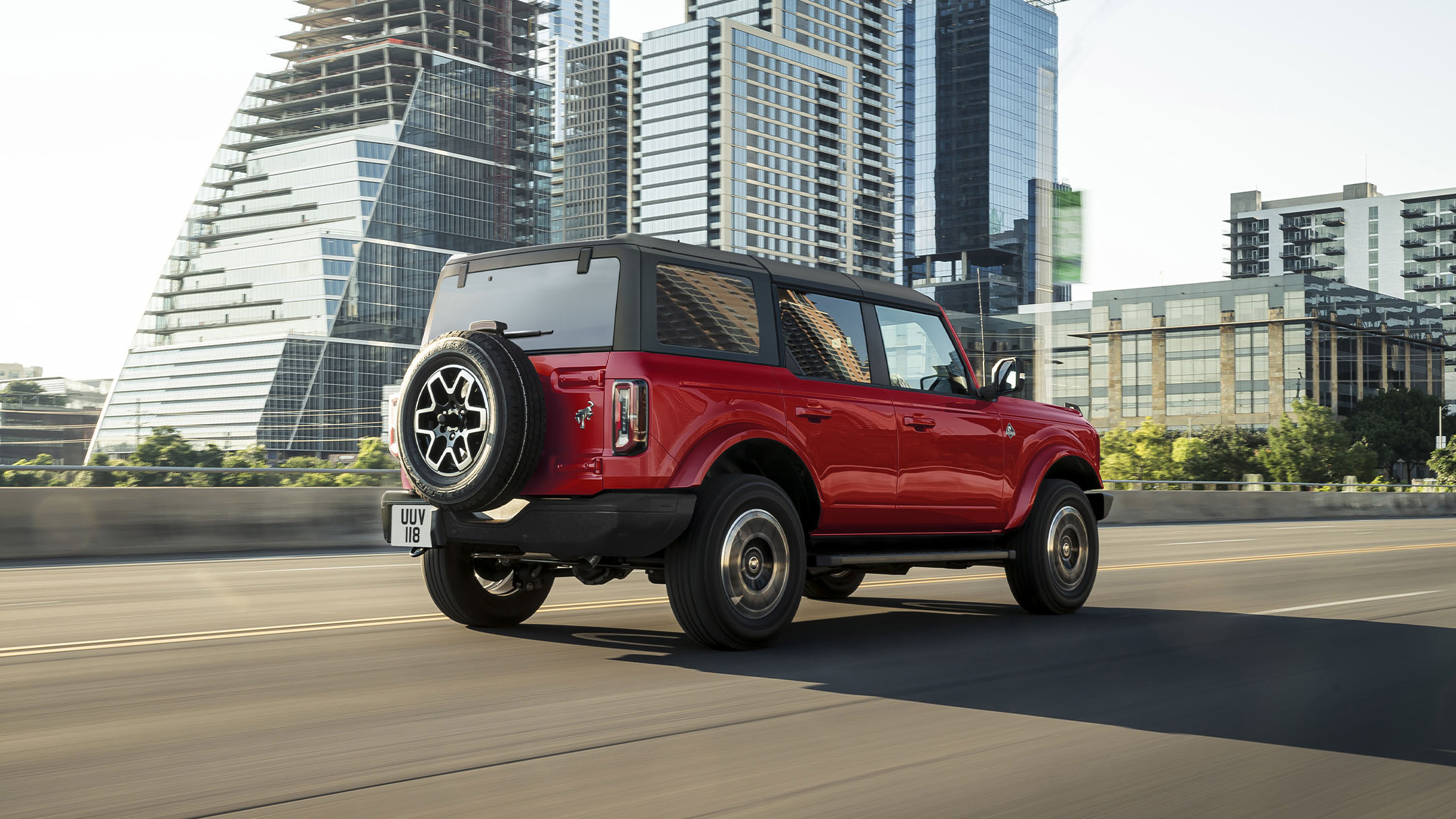 Ford Bronco en rouge. Vue arrière de 3/4. Traversant la ville