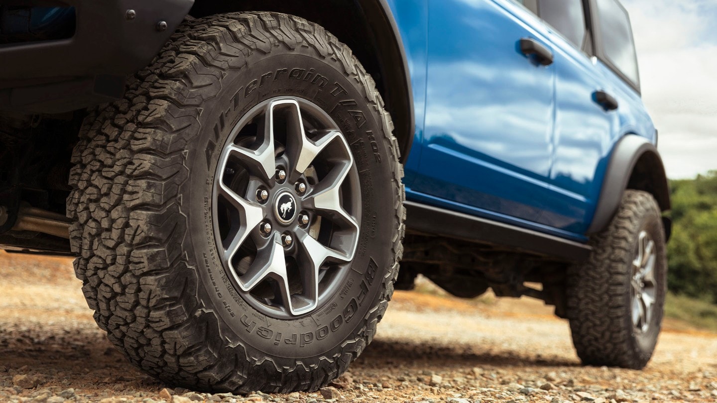 Ford Bronco en bleu, debout. Vue détaillée des roues avant et arrière