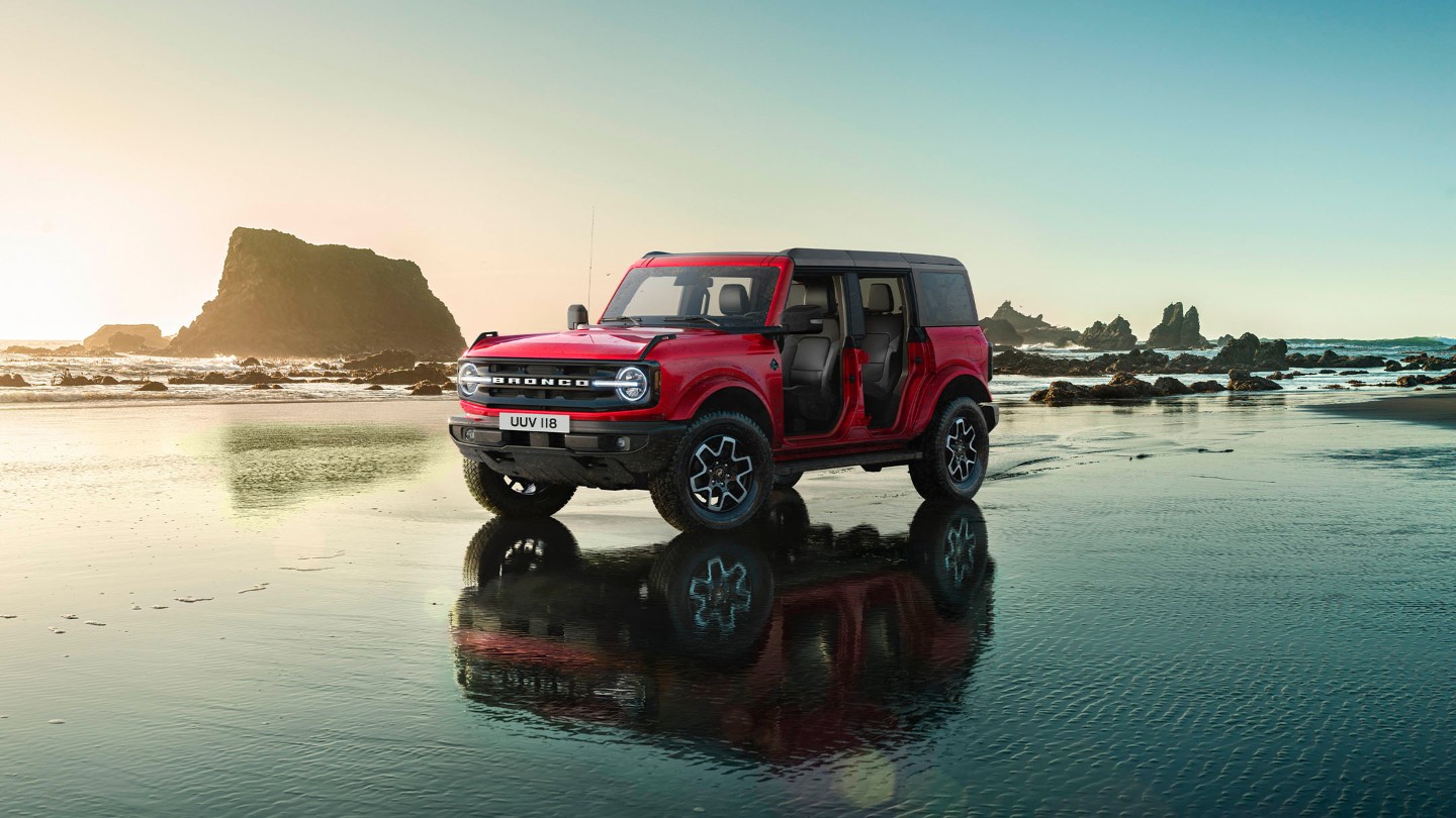 Ford Bronco en rouge, debout sur une surface recouverte d'eau, les portes enlevées