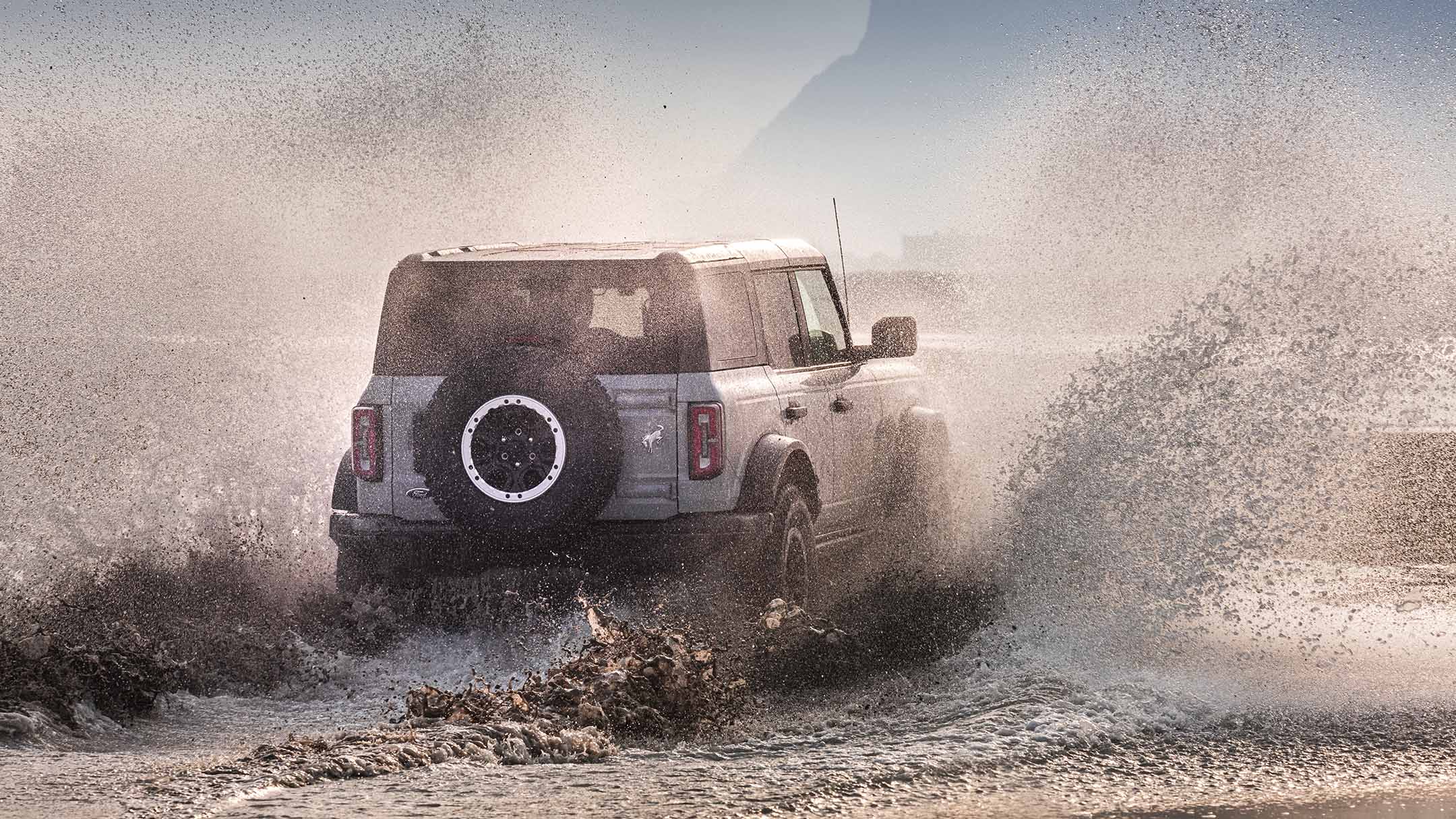 Ford Bronco en gris, vue arrière, traversant une eau stagnante