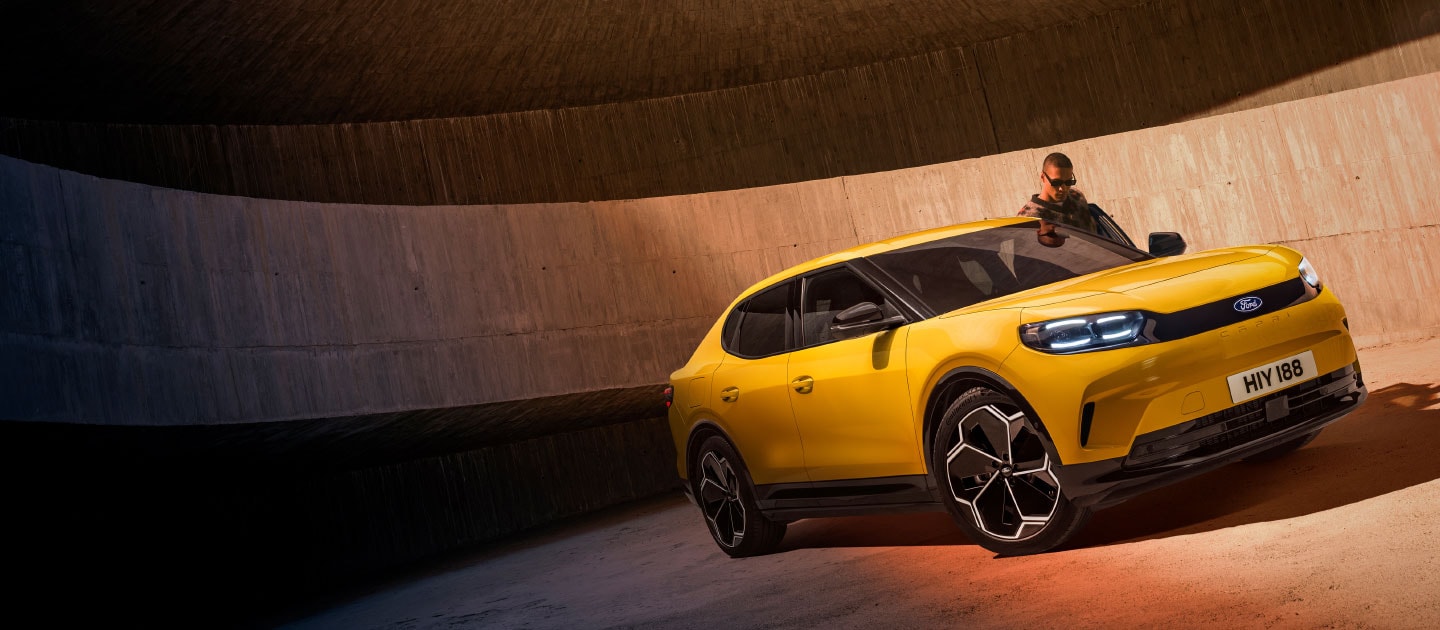 Un nouveau SUV Ford Capri® entièrement électrique jaune est stationné dans un parking.