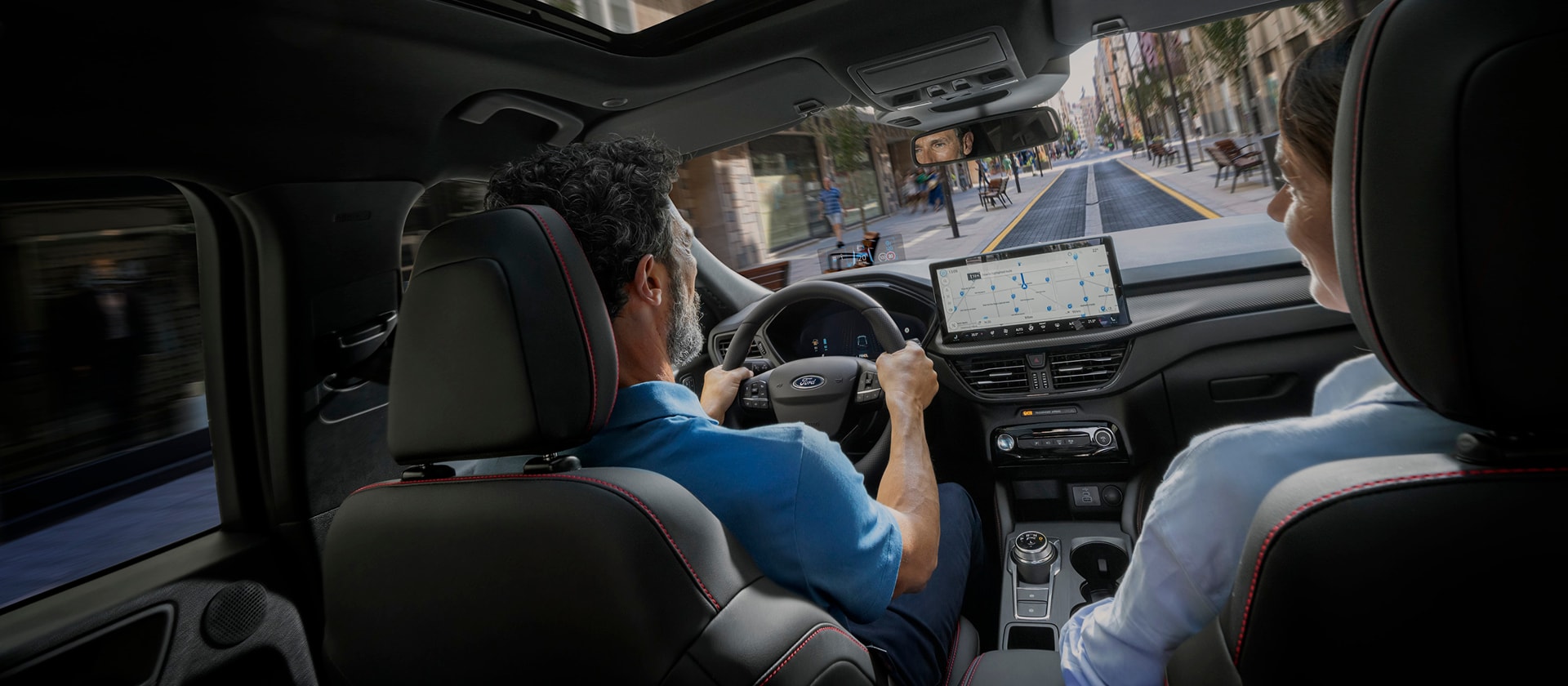 Le conducteur et la passagère d’un véhicule Ford utilisent SYNC sur l’écran numérique pour la navigation urbaine.