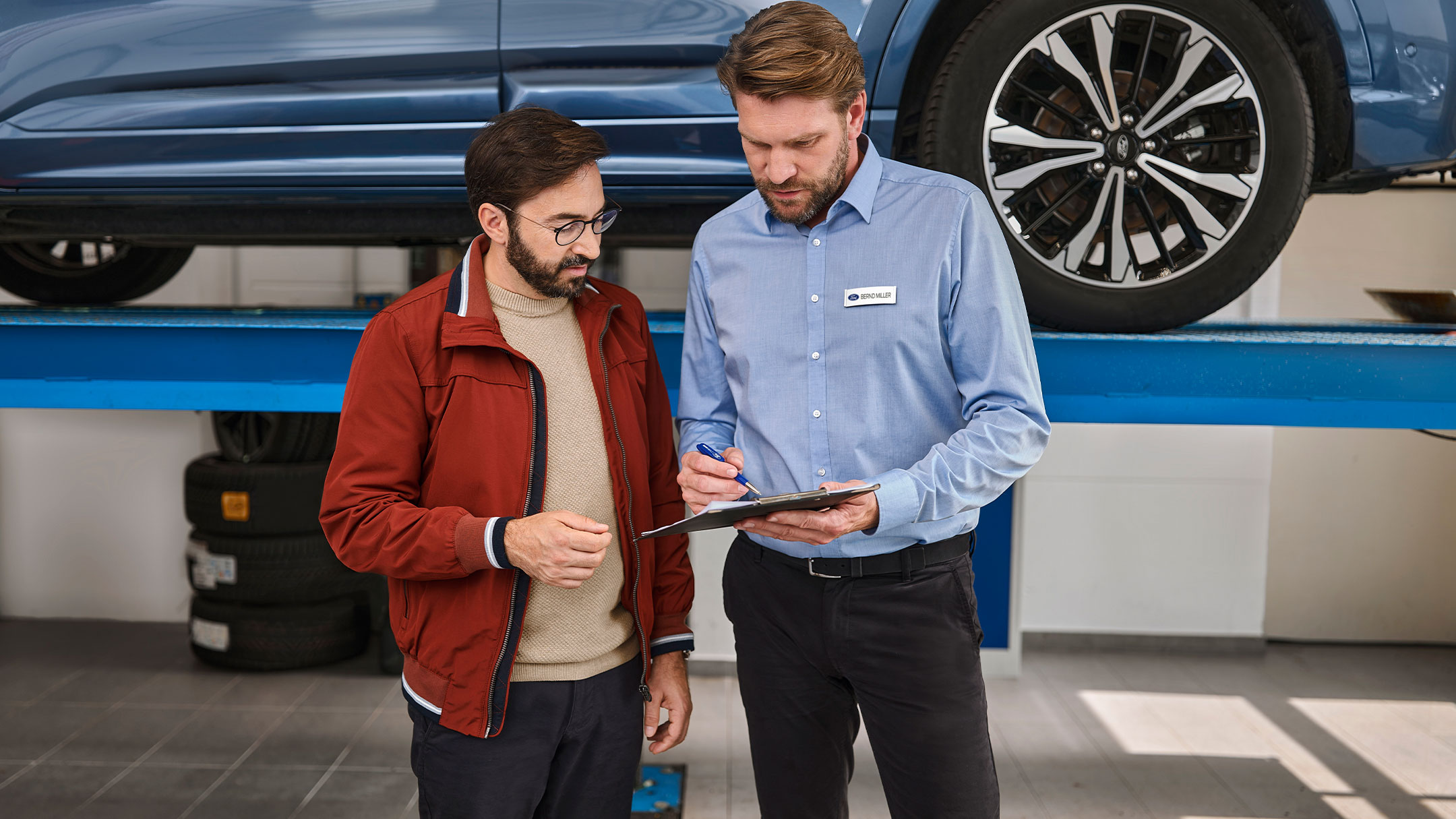 Un client discutant avec des experts Ford Service dans l’atelier d’un partenaire Ford.