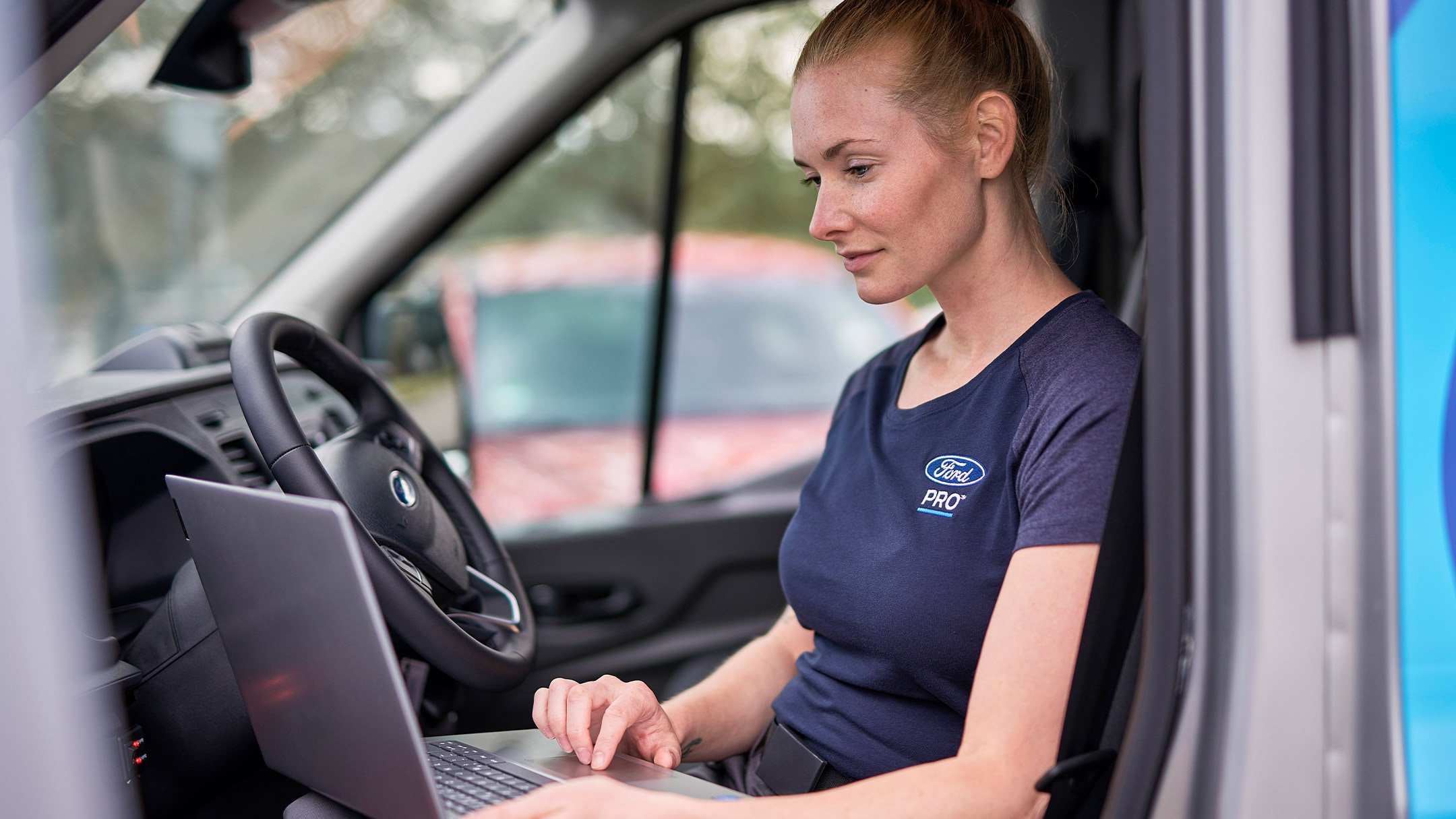 Une experte Ford Pro consulte son ordinateur portable pendant l’entretien Ford Service.