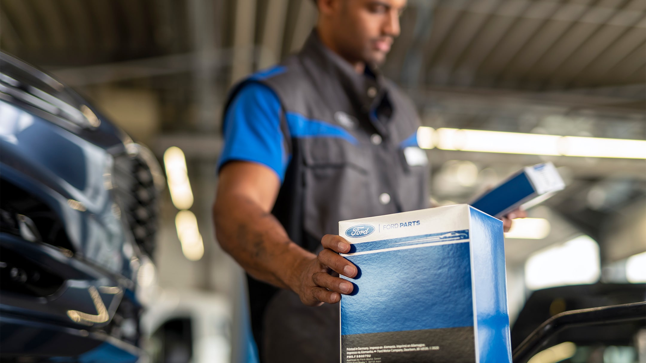 Un technicien Ford tenant l’emballage d’une pièce d’origine Ford pendant l’entretien.