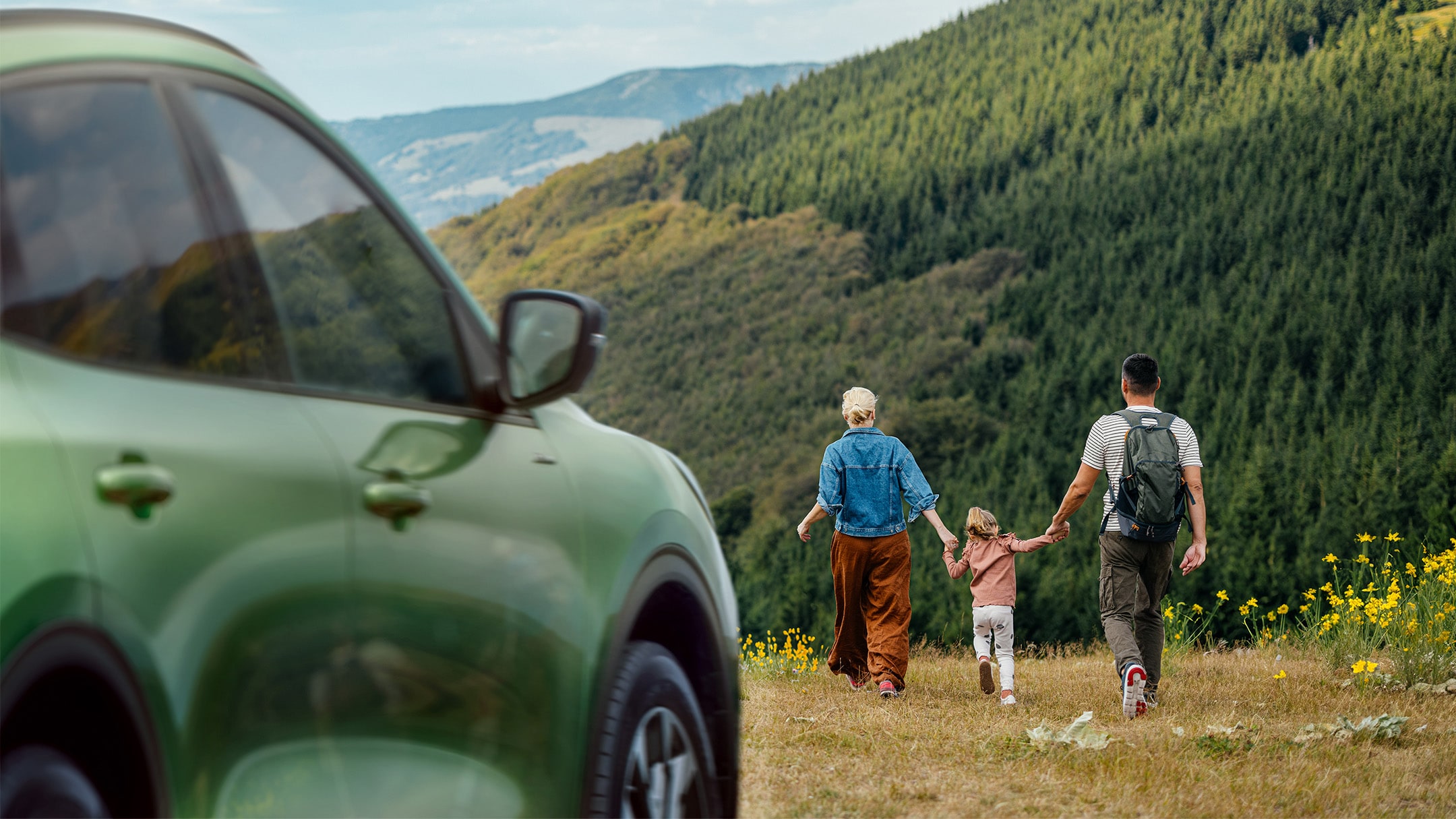 Family walking in a field by a green Ford Kuga Family walking in a field by a green Ford Kuga